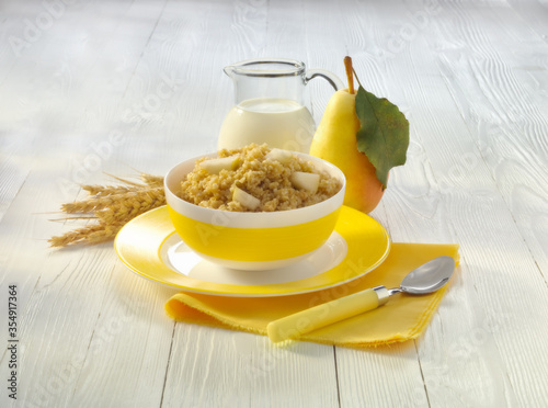 a bowl of millet porridge with a pear on the table photo