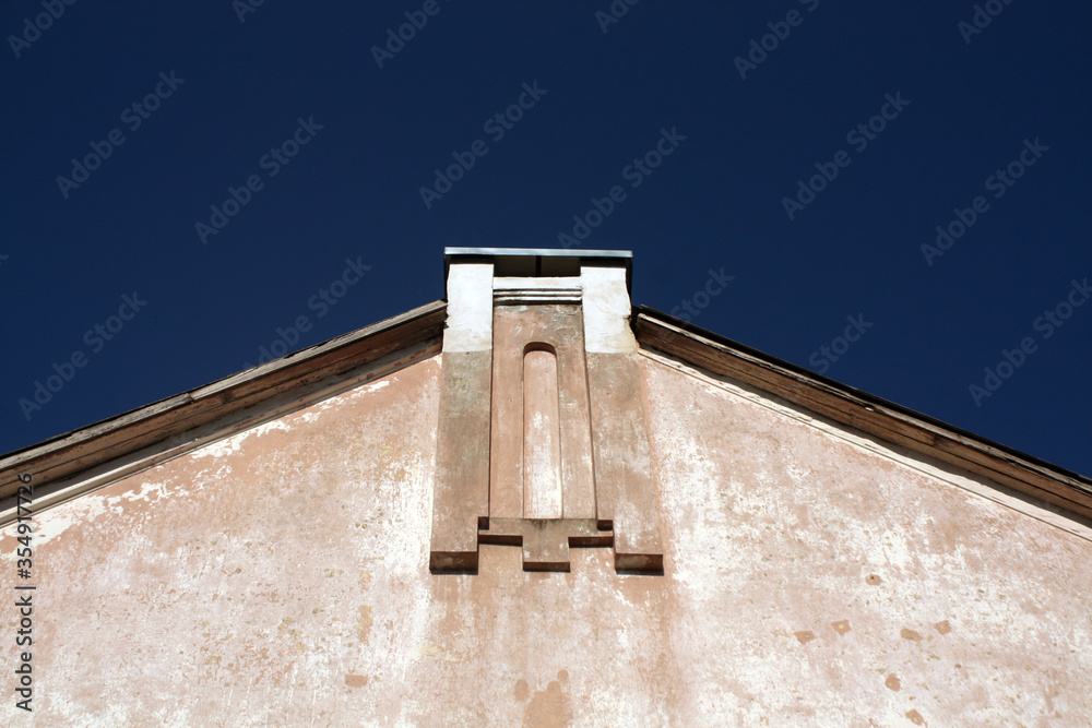 Wall and roof of old house against blue sky.