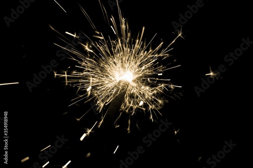 Yellow sparkler countdown on fire with spread of glitter sparks. Luxury entertainment at e.g. New Years Eve  Independence Day or birthday party celebration. Glowing light spark on dark background