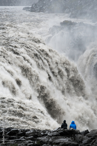 Close up of a huge raging icelandic waterfall with a black rocky shore in the foreground