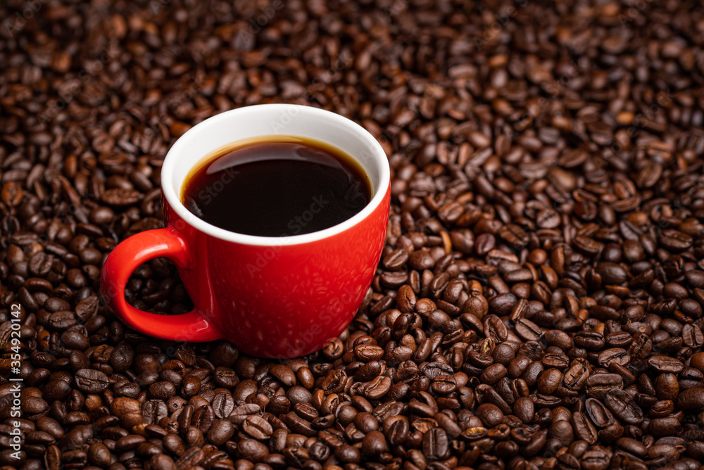 Red Cup of black coffee on table covered with coffee beans. Red Cup of black coffee on table covered with coffee beans.