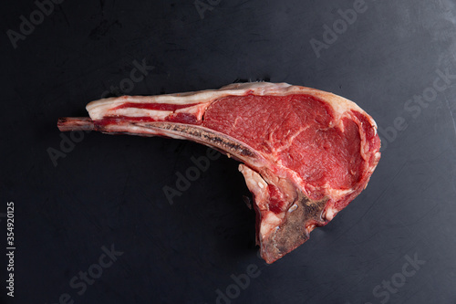 Classic raw bone steak on black background. Close-up