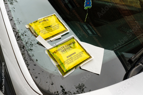 Two penalty charge notice parking fine attached to car windscreen