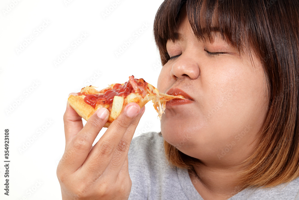 Fat Asian woman eating pizza happily. The concept of weight loss, choosing foods that are good for the body and health. White background. isolated Fat Asian woman eating pizza happily. The concept of weight loss, choosing foods that are good for the body and health. White background. isolated