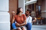 Young couple laughing and talking while eating doughnuts