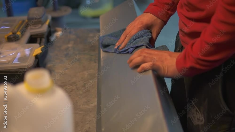 The worker's hand wipes the metal product with a cloth with a degreaser The worker's hand wipes the metal product with a cloth with a degreaser