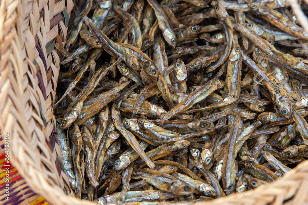 Brown woven basket filled with small dried fish