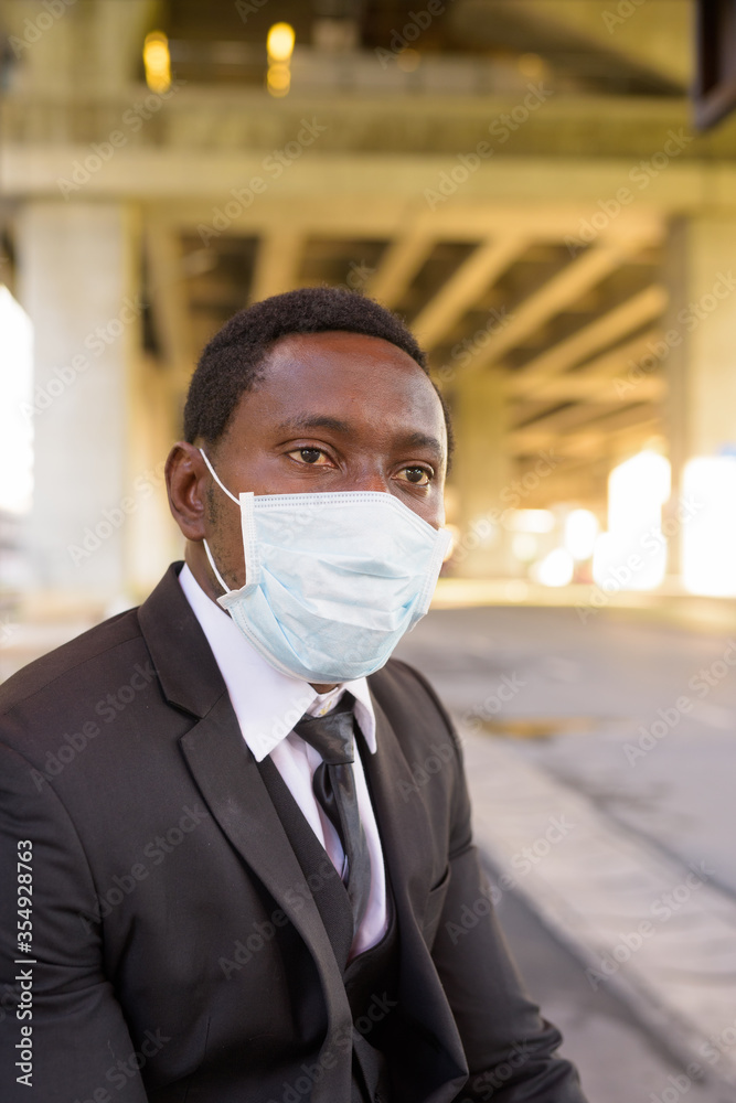 African businessman with mask thinking and waiting at the bus stop