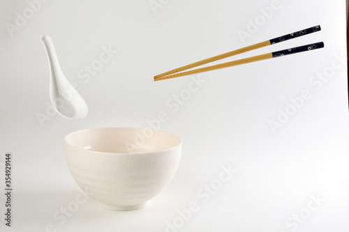 Empty oriental Japanese Chinese soup bowl spoon chopstick elevated flying in air off white