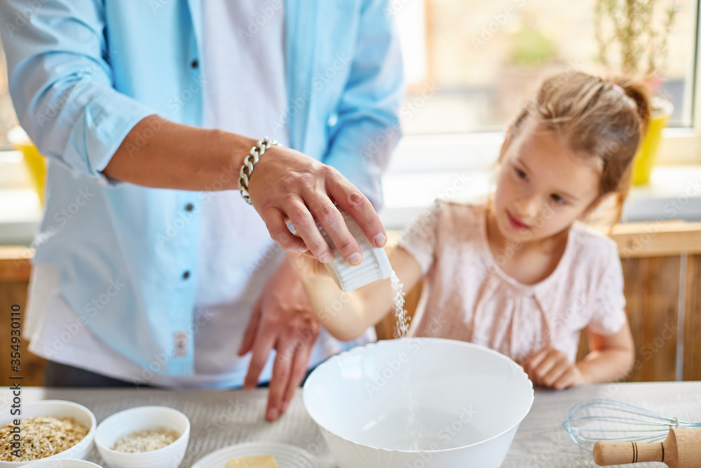 Father and daughter preparing dough together in kitchen Father and daughter preparing dough together in kitchen