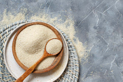 Raw uncooked fonio seeds with a spoon on a plate on grey background photo