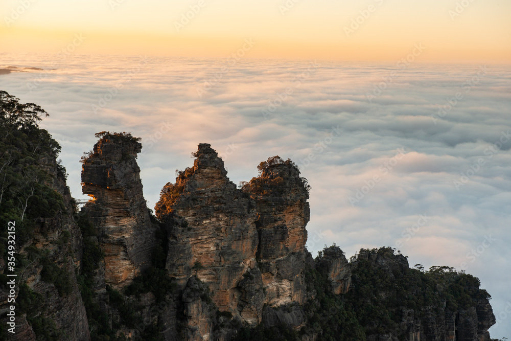 The famous Three Sisters sandstone rock formation of the Blue Mountains in New South Wales, Australia during morning with mist in valley.