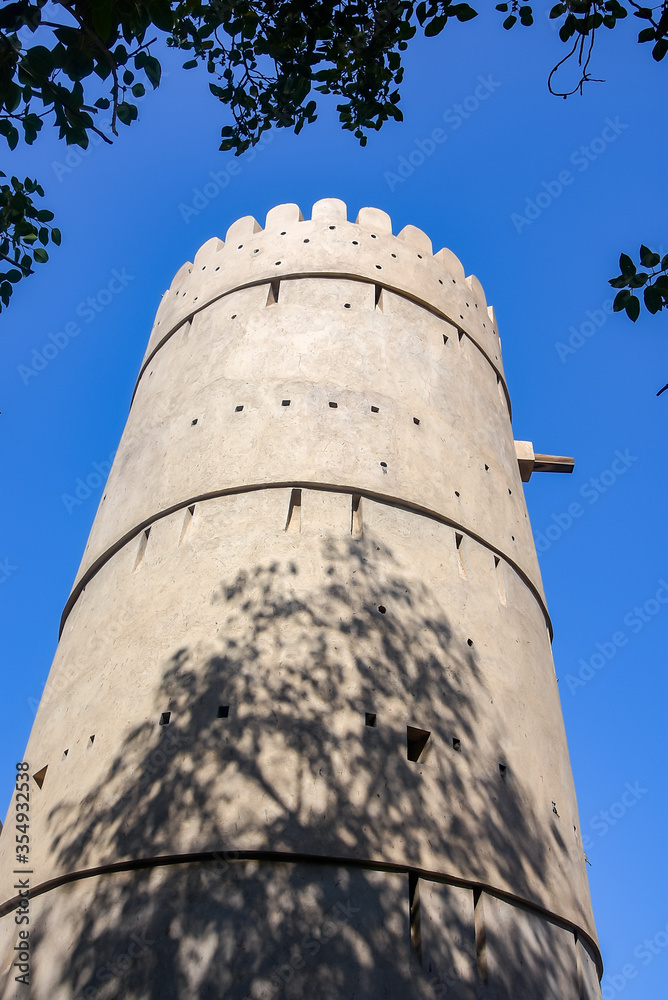 Fort watch tower in the the ancient city of Nizwa, Oman with cloudless blue sky behind it
