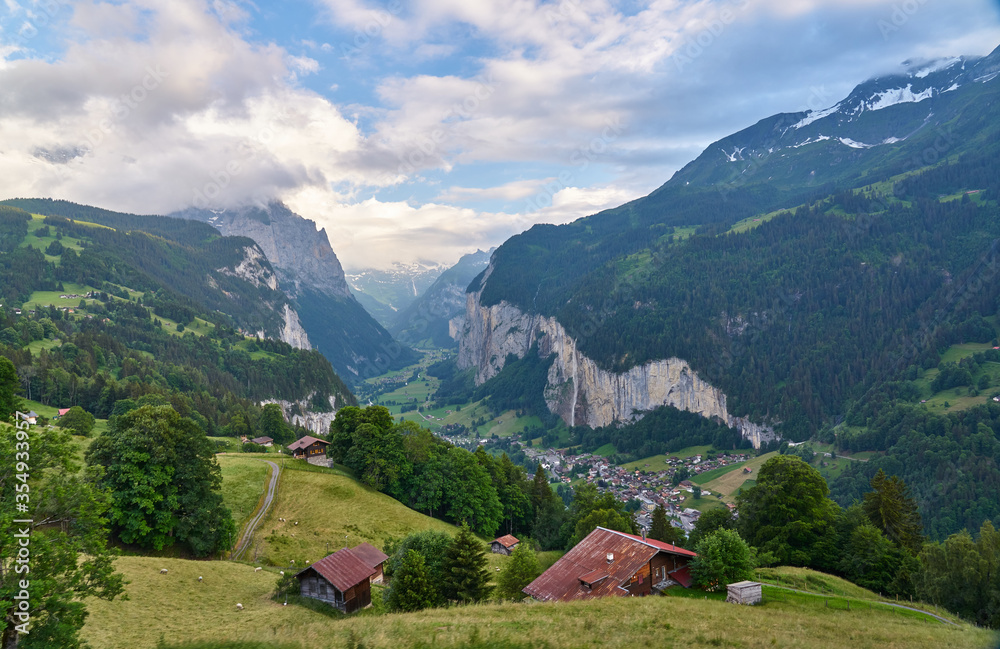 Lauterbrunnen Valley at sunset with snowy mountains, waterfall and green nature. Landscape panorama taken from mountain village Wengen, Switzerland