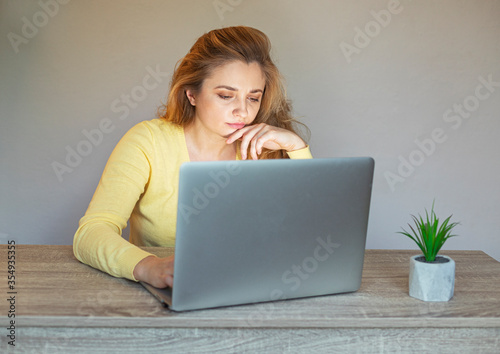 Tired woman with a laptop .Problem with a laptop. Girl with a laptop sits at the table