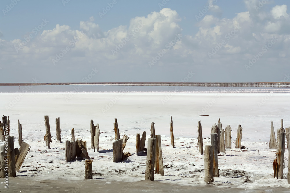 Abandoned salt industry. Pink salt lake. Salt mining. Industrial landscape and the beauty of nature. Shiny crystals of salt, reflection of clouds in the water. Salt crust marks Abandoned salt industry. Pink salt lake. Salt mining. Industrial landscape and the beauty of nature. Shiny crystals of salt, reflection of clouds in the water. Salt crust marks