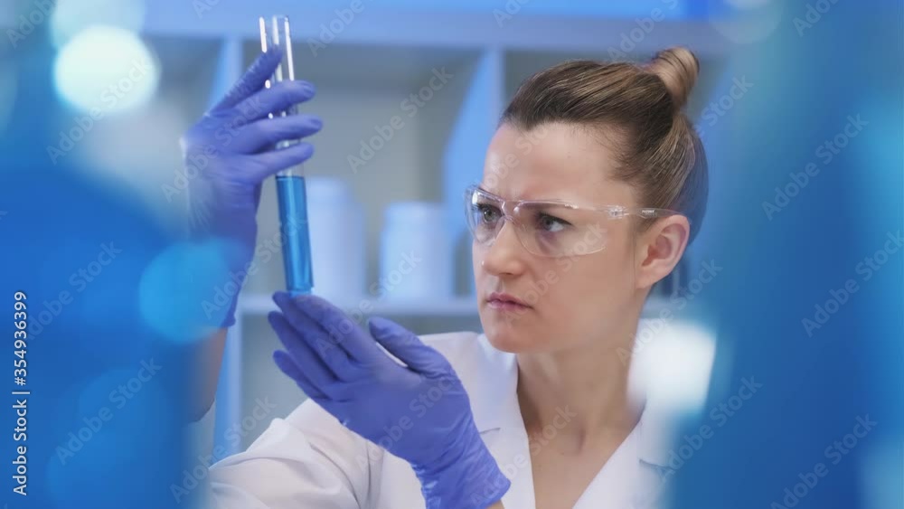 A female medical scientist works in a laboratory. Spcialist conducts experiments with fluids in test tubes, develops auccin auctin from the virus. Coronavirus covid-19. A female medical scientist works in a laboratory. Spcialist conducts experiments with fluids in test tubes, develops auccin auctin from the virus. Coronavirus covid-19.