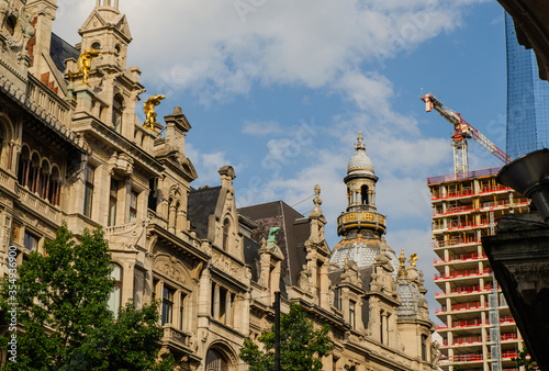 Antwerp, Flanders, Belgium. August 2019. Historic center: on the left the splendid Renaissance buildings and on the right the construction site of a modern skyscraper. The red and white crane appears. © Massimo Parisi