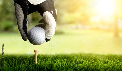Hand of golfer putting golf ball on the tee.