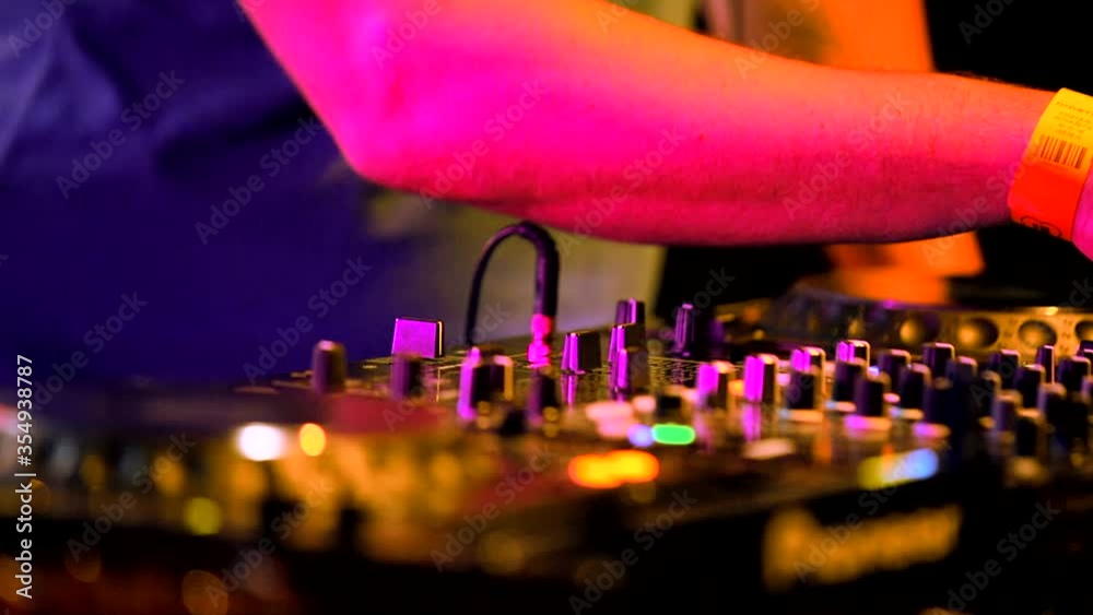 DJ play the music on the mixing console in the discotheque at night