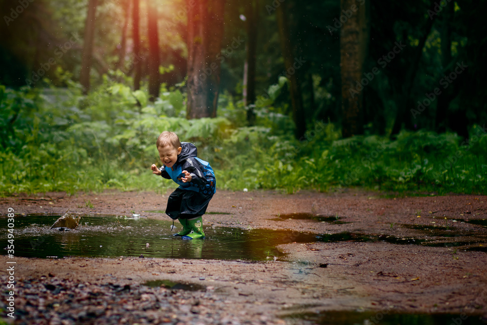 A little boy is jumping in a muddy puddle. Image with selective focus and toning A little boy is jumping in a muddy puddle. Image with selective focus and toning