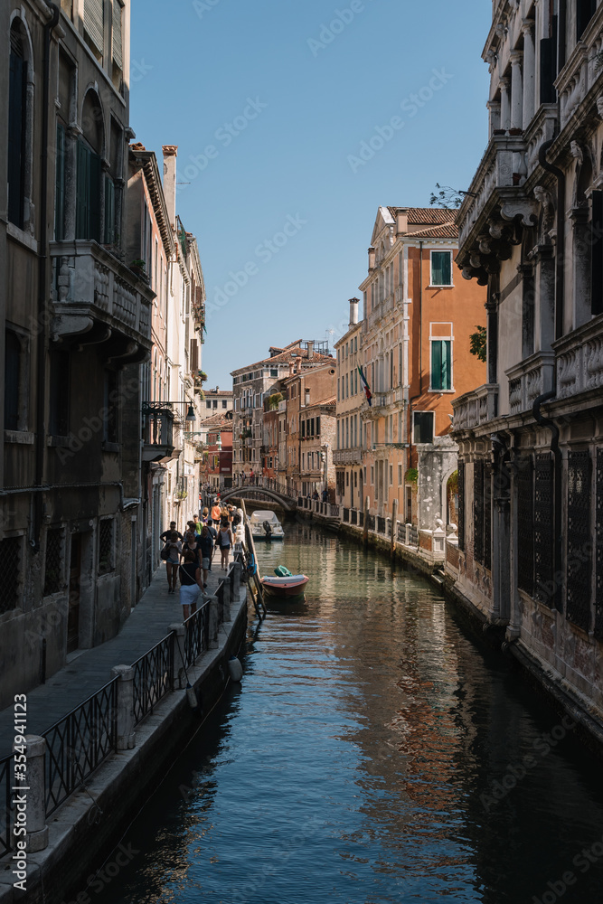 People are walking along a canal in Venice, Italy.