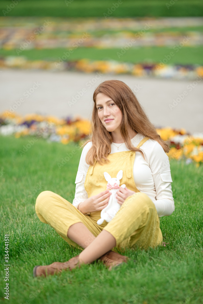 Expecting young female mother posing in park holding plush toy