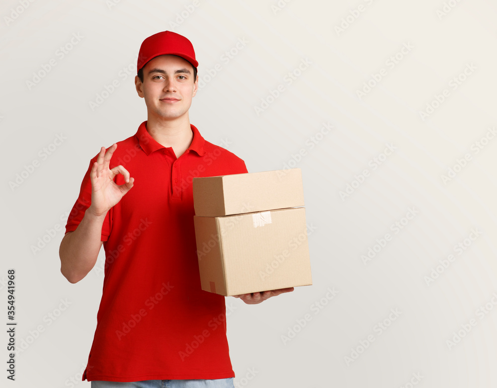 Excellent job. Deliveryman holding parcels in hand and shows sign perfectly with his hand Excellent job. Deliveryman holding parcels in hand and shows sign perfectly with his hand