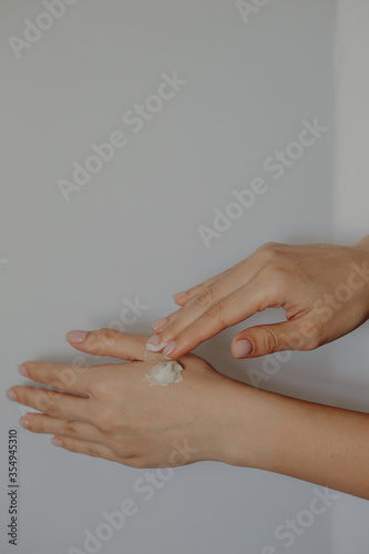 A woman holds a cream tube and applying moisturizer to her beautiful hands for clean and soft skin. Female applying cream to her hands. beautiful woman hands with cream.