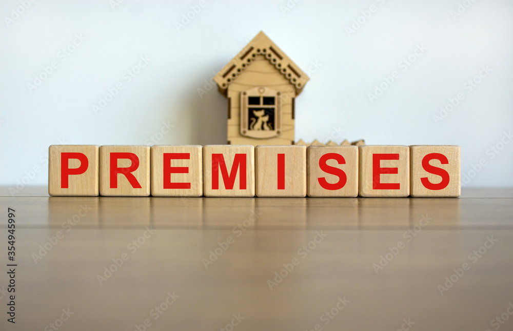 Wooden cubes form the word 'premises' near miniature house. Wooden table. Beautiful white background, copy space. Wooden cubes form the word 'premises' near miniature house. Wooden table. Beautiful white background, copy space.