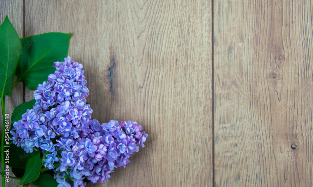 Fototapeta premium Lilac branch on beautiful wooden table. Concept. Beautiful background, copy space.