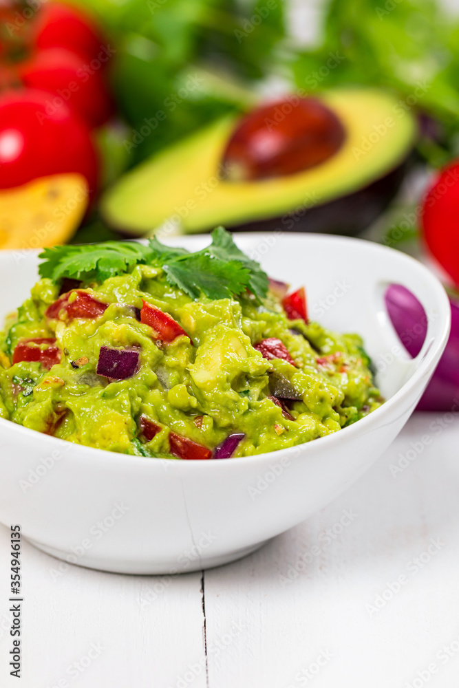 Bowl of Guacamole next to Fresh Ingredients on a Table with Tortilla Chips. Selective focus. Bowl of Guacamole next to Fresh Ingredients on a Table with Tortilla Chips. Selective focus.