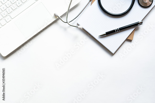 Workplace of doctor with laptop and stethoscope on keyboard and notepad with pen isolated. Close up. Concept medical, business.
