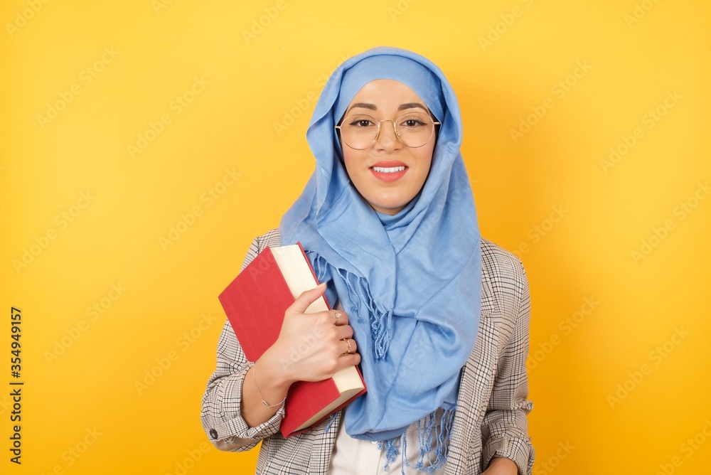 Confidence and business concept. Portrait of charming successful young muslim woman wearing hijab, smiling broadly with self-assured expression while. Confidence and business concept. Portrait of charming successful young muslim woman wearing hijab, smiling broadly with self-assured expression while.