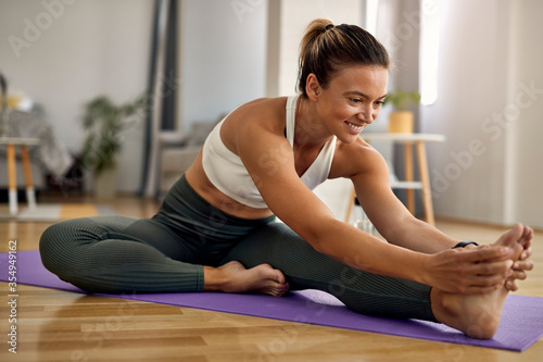 Happy athletic woman stretching her leg while exercising at home.