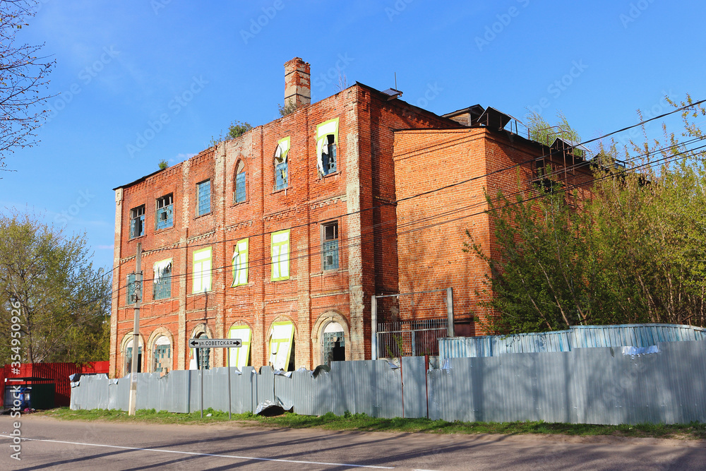Side view of an historic abandoned brick building with broken windows of the Zaraysky feather factory founded in 1858 by German businessman August Reders. Translation: 