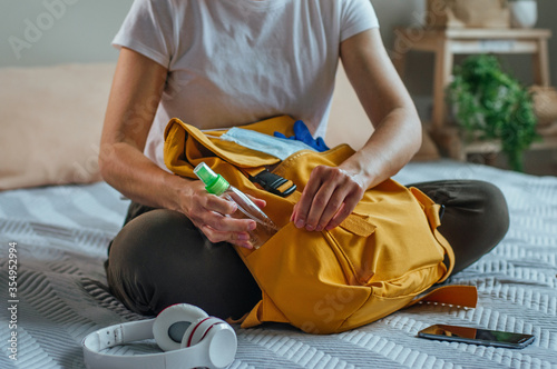 Close up of young woman packing her backpack with hand sanitizer