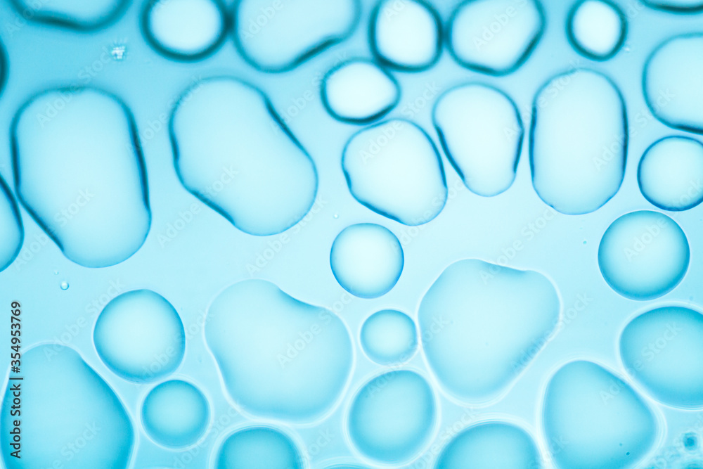 Image from microscopy of water drops in the microscopic slide.Abstract oxygen bubbles in the water.Mixed and different shape background in the blue tone.