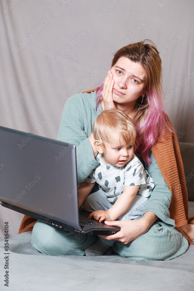 A young woman works at home with a laptop, along with a child.the son wants to communicate with his mother, they make noise and interfere with work.isolation during the coronovirus pandemic A young woman works at home with a laptop, along with a child.the son wants to communicate with his mother, they make noise and interfere with work.isolation during the coronovirus pandemic