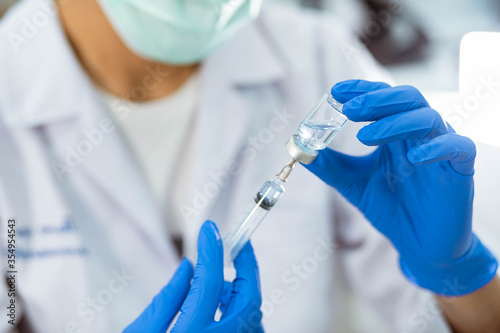 Doctor in blue glove filling syringe with vaccine
