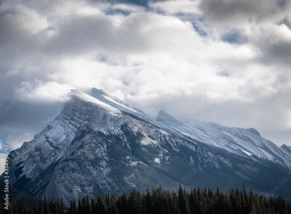 Snowy mountain (Mount Rundle) covered by snow and shrouded by clouds, detail shot made at Vermilion Lakes, Banff National Park, Alberta, Canada