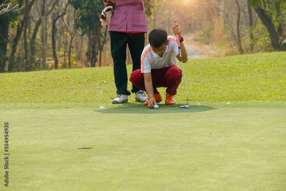 Obraz premium Golfer playing golf in the evening golf course, on sun set evening time. Man playing golf on a golf course in the sunset background