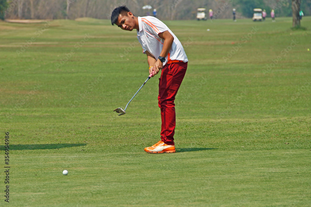 Golfer playing golf in the evening golf course, on sun set evening time. Man playing golf on a golf course in the sunset background Golfer playing golf in the evening golf course, on sun set evening time. Man playing golf on a golf course in the sunset background
