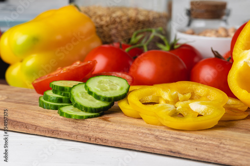 Cut vegetables on wooden board. Bell pepper, tomatoes and cucumbers