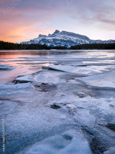 Colorful sunset on frozen lake with isolated mountain in background, shot during sunset at Two Jack Lake, Banff National Park, Alberta, Canada
