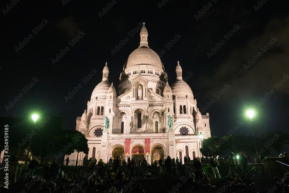 Basilica Sacré Coeur, famous church in the district of Montmartre, Paris by night. Exterior enhanced by lighting.