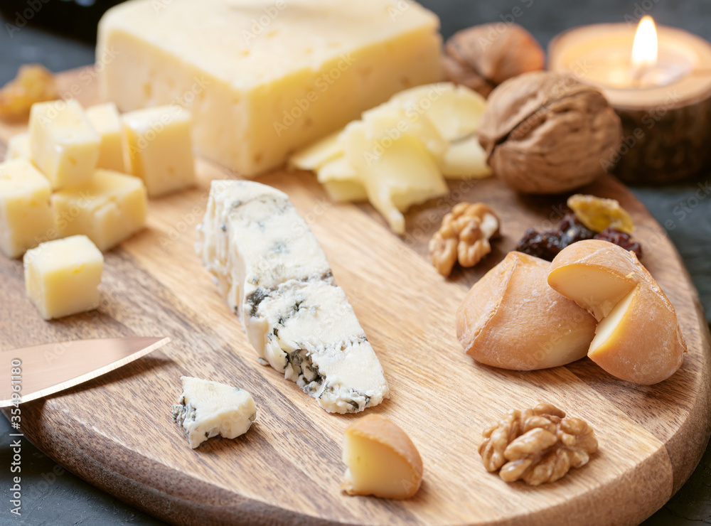 Cheese plate from different kind of cheese - Emmental, Homemade, Parmesan, blue cheese, bread sticks, walnuts, raisin, pear, grapes on a table Cheese plate from different kind of cheese - Emmental, Homemade, Parmesan, blue cheese, bread sticks, walnuts, raisin, pear, grapes on a table