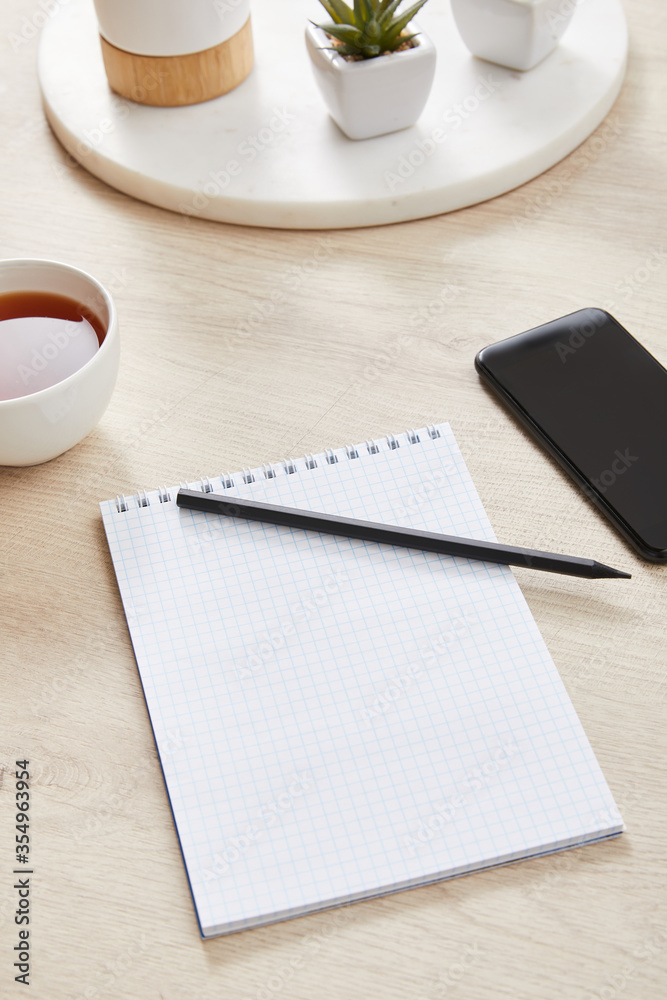 green plant, cup of tea and blank notebook with pencil near smartphone on wooden surface green plant, cup of tea and blank notebook with pencil near smartphone on wooden surface