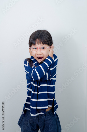 Portrait of little kid boy isolated over white background showing tongue. Funny little power super hero kid showing muscles. Image of a little toddler surprise, a little girl standing alone over 
