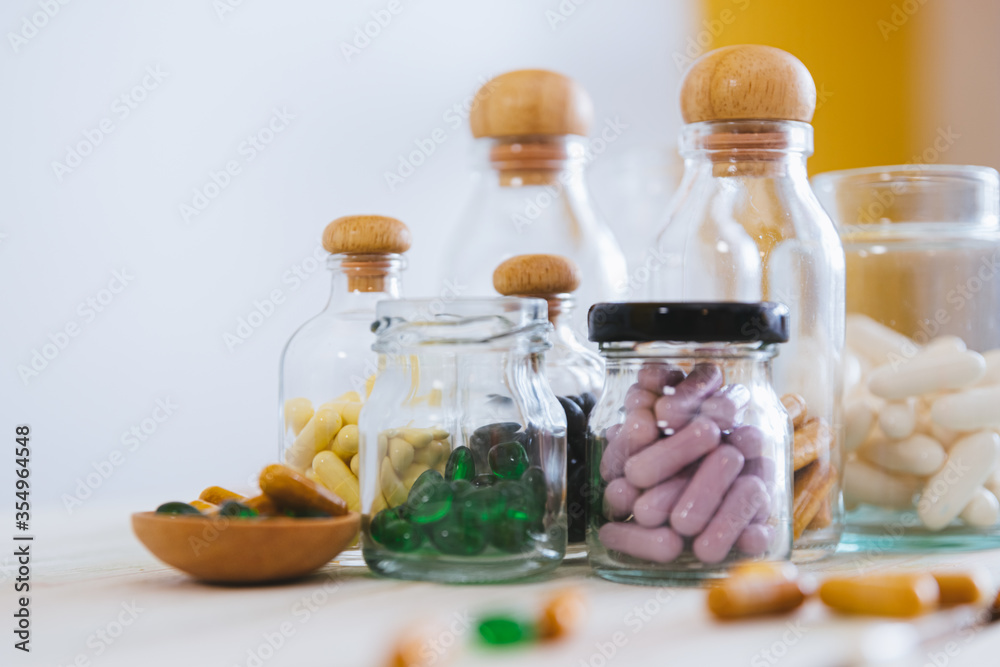 Close up pill and tablet medicine in glass bottle on wooden table. Medical concept, virus treatment, healthcare. Close up pill and tablet medicine in glass bottle on wooden table. Medical concept, virus treatment, healthcare.